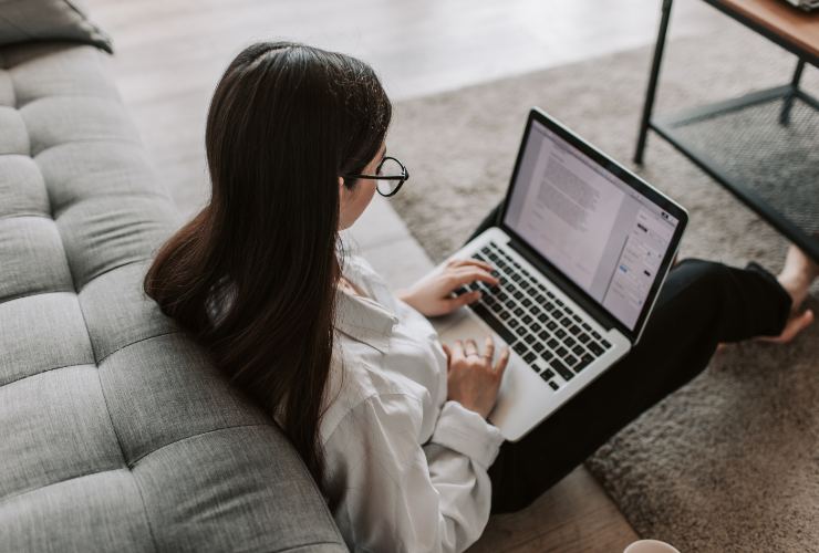 ragazza che lavora al pc sul divano