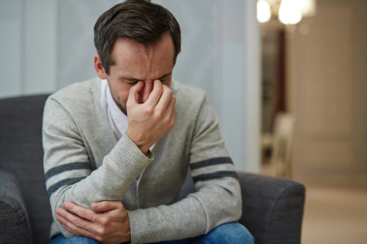 uomo seduto disperato con una mano sulla faccia