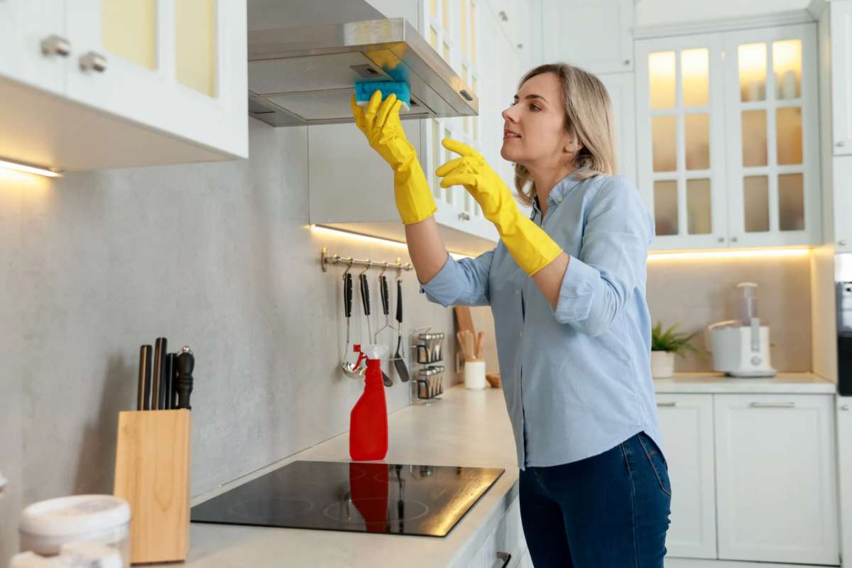 Donna bionda che pulisce cucina con una spugna