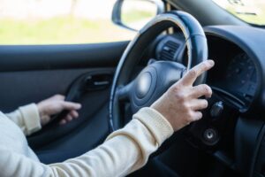 donna in auto chiude portiera e tiene volante con una mano