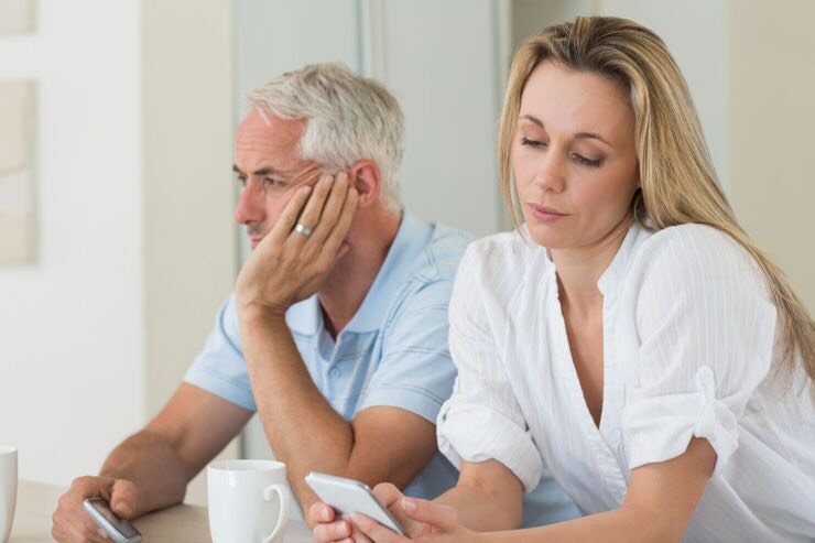 Coppia, lei al cellulare, lui pensieroso 