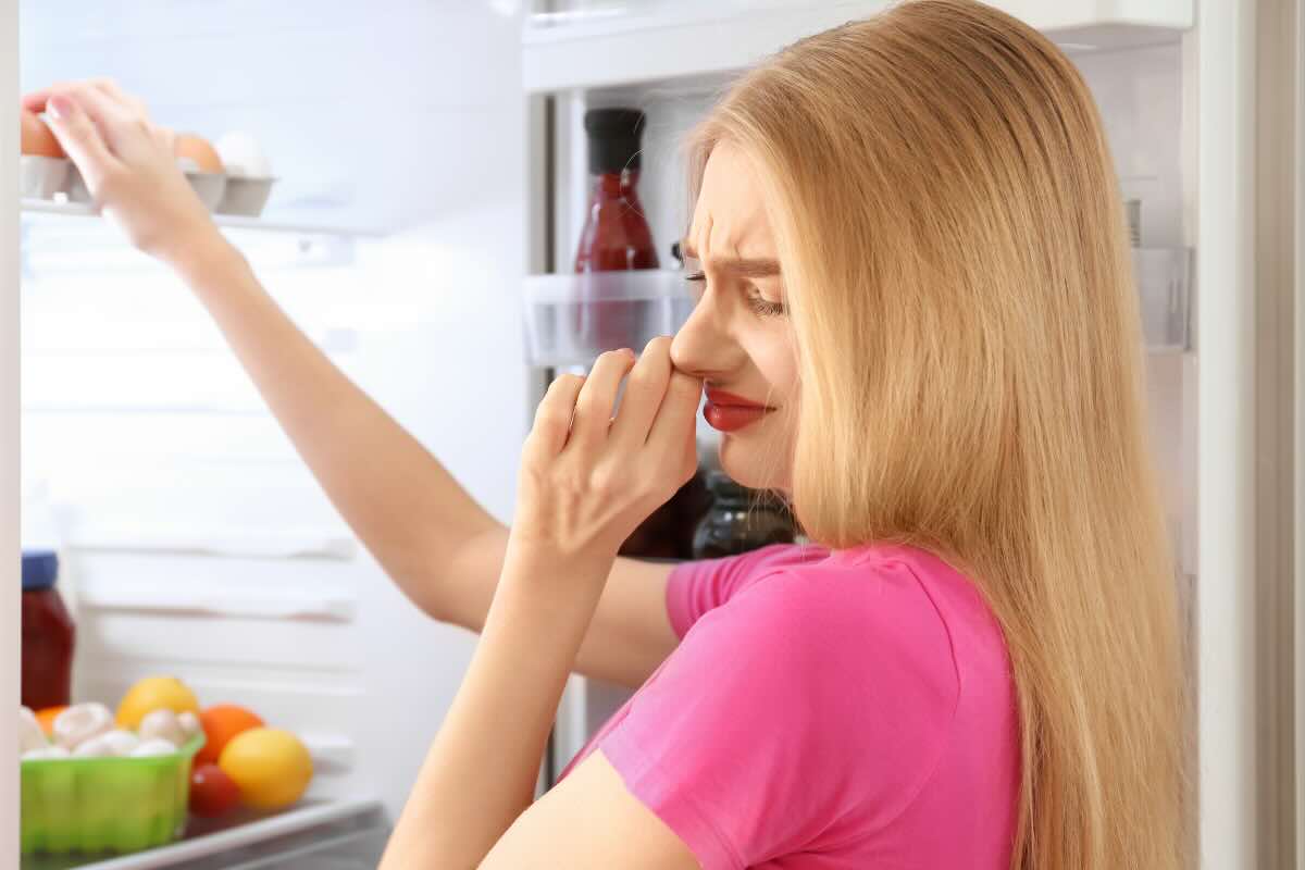 donna che si tappa naso aprendo frigo