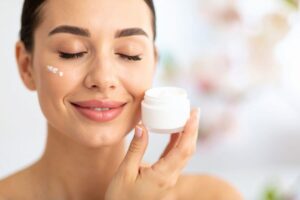 Donna con vasetto di crema e crema sul viso