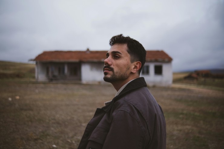 uomo preoccupato e sullo sfondo casa vecchia