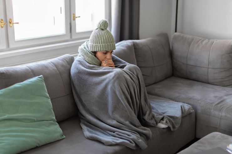 donna con coperta e cappello seduta sul divano