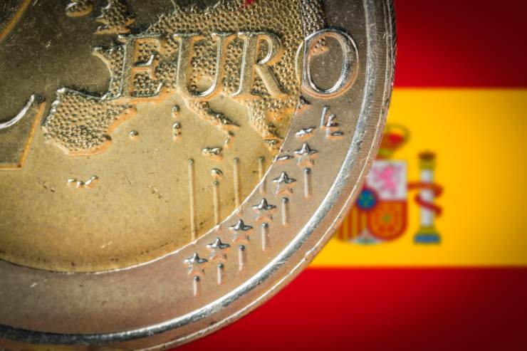 moneta due euro spagnola con bandiera in secondo piano