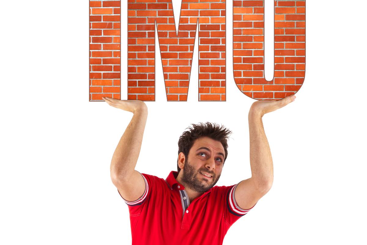 uomo tiene con fatica con le mani la scritta imu