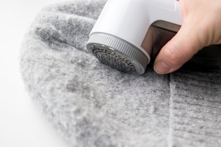 Persona che toglie i pelucchi da un maglione con il rimuovi pilling