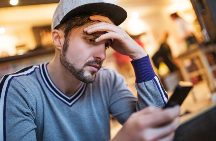 uomo preoccupato mentre guarda il cellulare
