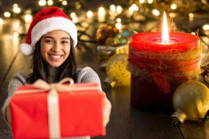 Ragazza cappello Natale e pacco regalo, candela rossa accesa