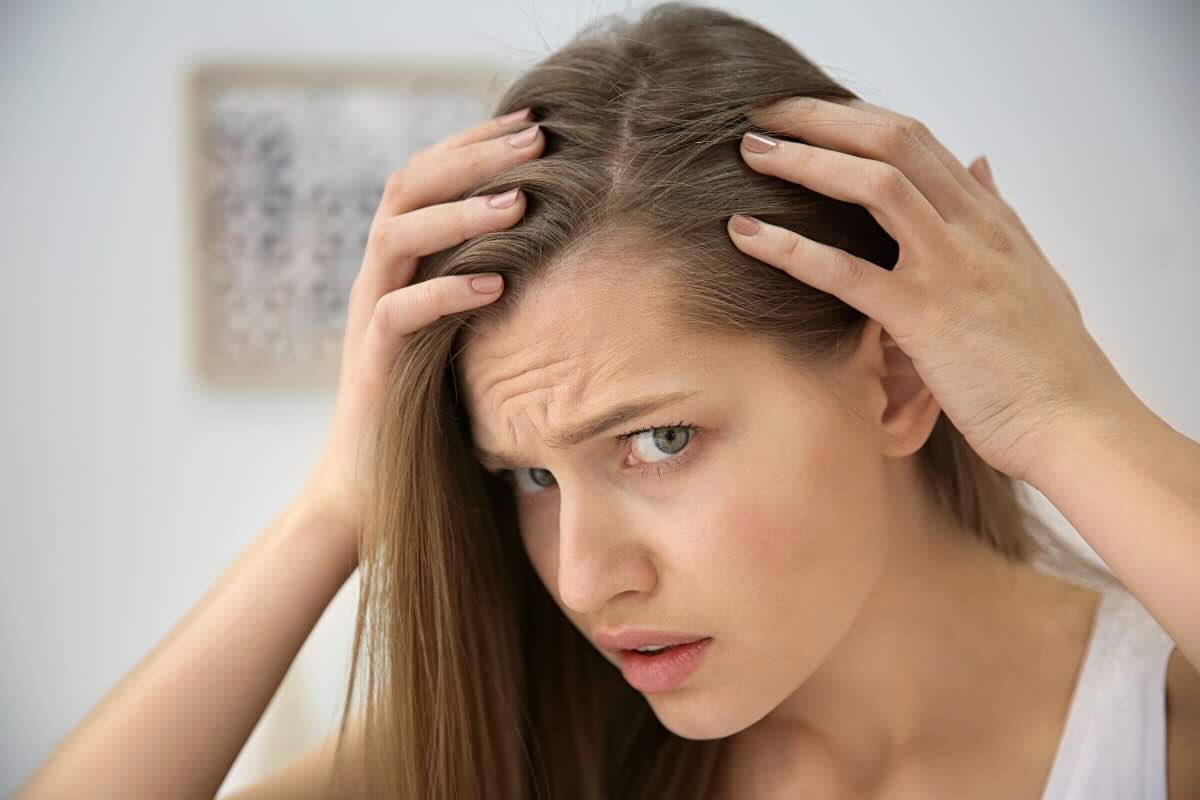 donna che si tocca radice capelli