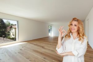 stanza vuota con parquet e donna bionda che fa ok con le mani