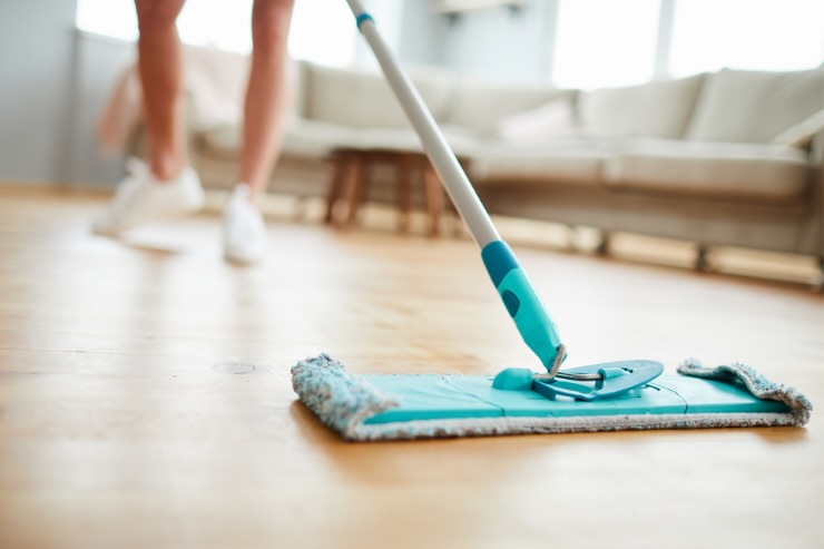 piedi di persona con straccio per lavare a terra il parquet